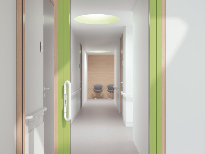 Glazed hospital door with green frame equipped with a lever handle in the colour signal white made of polyamide