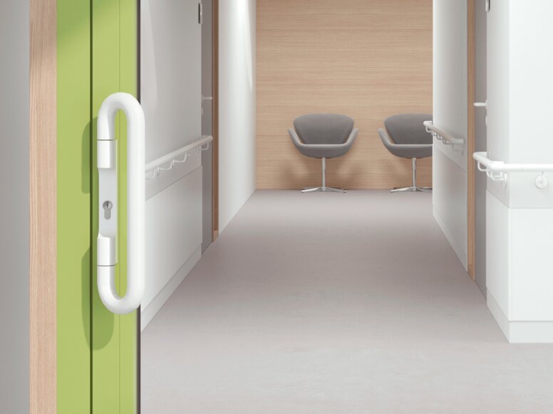 Glazed hospital door with green frame equipped with a lever handle in the colour signal white made of polyamide