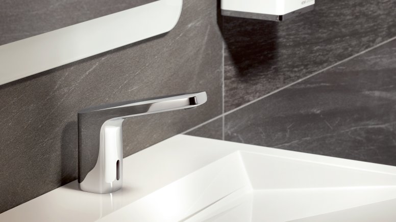 Touchless, chrome-plated mixer tap on a white washbasin